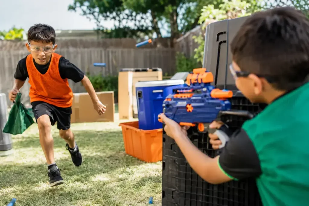 Kids playing Nerf capture the flag with blasters and eye protection in a backyard